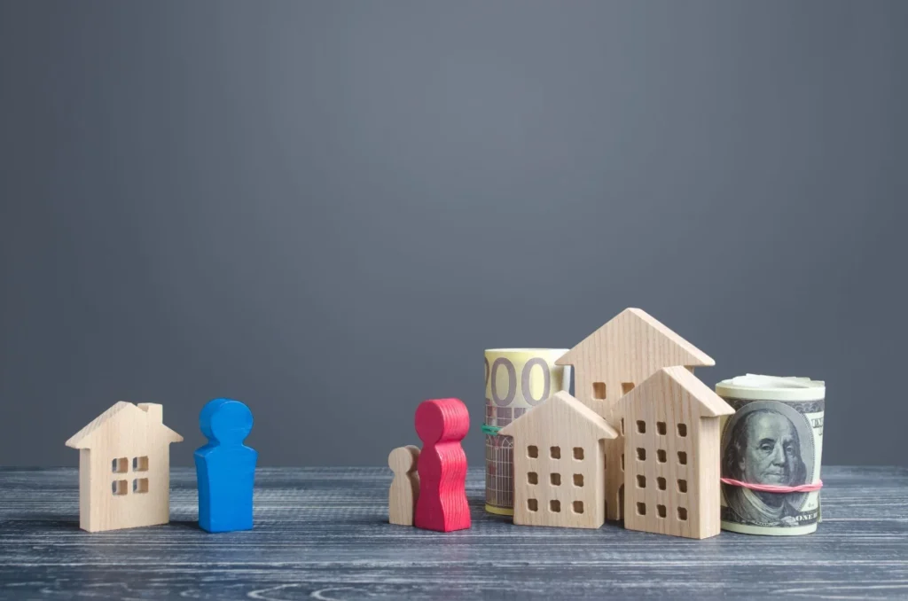 Wooden house and family figures with rolled banknotes, symbolizing property division, child custody, and financial settlements in divorce.