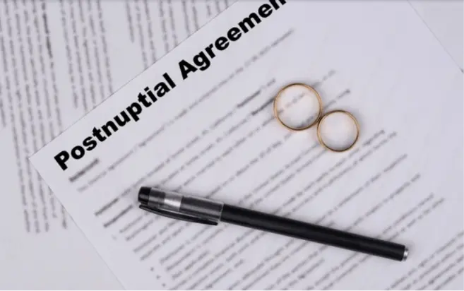 Postnuptial agreement document with wedding rings and a pen on top.