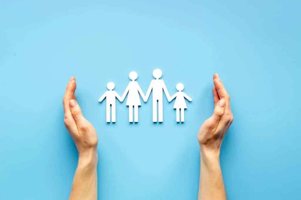 Symbolic paper family protected by caring hands, representing child adoption and family support
